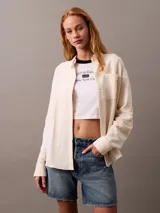 Camisa color crema de gasa doble, con cuello de punta, bolsillo de parche en el pecho, mangas largas con cierre de solapa enrollable y corte regular.