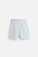 Bermuda azul de corte relaxed fit, confeccionada en tejido interlock de algodón con cintura elástica ajustable con cordón, bolsillos laterales y bolsillo trasero de plastrón.