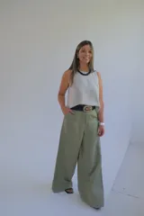 Pantalón verde oliva de corte palazzo, con cintura alta y pernera ancha. Incluye cinturón trenzado negro con hebilla metálica decorada.