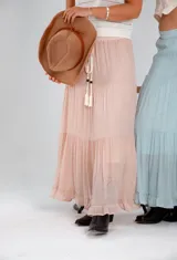 Pollera larga color rosa pálido, de voile de algodón y viscosa, con tres volados y cordón ajustable en la cintura.