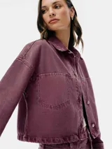 Chaqueta de denim color borgoña, con cuello clásico, cierre frontal con botones metálicos, mangas largas y bolsillos de parche en el pecho.