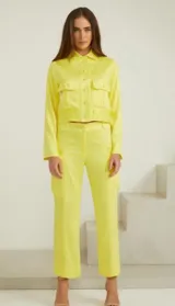 Chaqueta de algodón color amarillo vibrante, entallada, con manga larga y bolsillos frontales.
