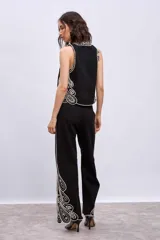 Pantalón blanco de corte ancho con bordados calados en forma de hojas en el ruedo.