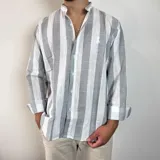 Camisa celeste y blanca a rayas verticales, de lino, con cuello mao y mangas largas con puños.