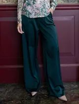 Pantalón palazzo de tiro alto color violeta, de satén. Tiene pretina delantera con pasadores, botón y cierre, pretina trasera elastizada y bolsillos verticales delanteros.