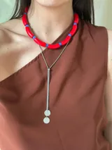 Gargantilla con cuentas de tubo acrílicas rojas y cristales checos azules. Se cierra con cadena de acero quirúrgico y ganchito para regular el largo.