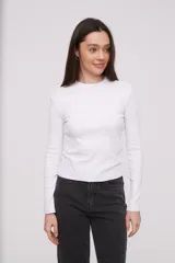 Polera blanca ajustada al cuerpo, de manga larga y diseño minimalista.