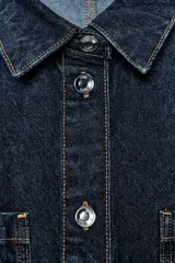 Mono corto de denim azul oscuro, con cuello solapa, manga corta, bolsillos delanteros y traseros, cintura elástica en la espalda y cierre frontal con cremallera y botones metálicos.