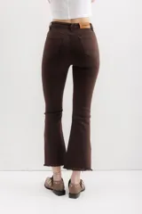 Pantalón jean marrón acampanado con detalle desflecado en el bajo y tiro medio.