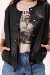 Chaleco negro de símil cuero suave con botones a presión y ruedo regulable.