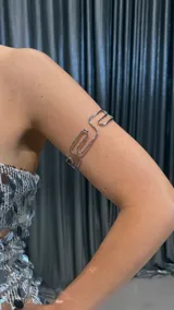 Brazalete plateado de metal con diseño geométrico.