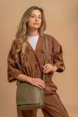 Bandolera de hombro color gris claro, con solapa frontal y correa ajustable. Presenta un diseño simple y práctico, ideal para uso diario.