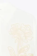 Camisa blanca de manga larga con cuello solapa y bordado de flor en el frente.