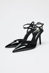 Zapato de tacón destalonado negro acharolado con tiras finas cruzadas ajustables con hebilla al tobillo y punta fina.
