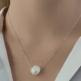 Collar de plata 925 con cadena fina y un dije central de perla de río barroca blanca, de forma irregular.