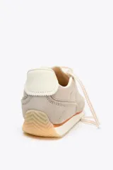 Zapatillas deportivas tipo running color beige y gris claro, con detalles en cuero y gamuza. Cierre con cordones.