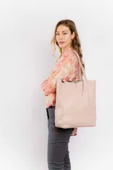 Bolso tote de cuero color beige, con doble asa de hombro y cierre superior con tira de cuero.