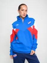 Buzo con medio cierre, color azul, con diseño de franjas en rojo y blanco, y logo del club.