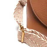 Bandolera pequeña de material símil cuero color habano, con solapa frontal y cierre superior. Presenta un logo metálico XL en el frente y herrajes dorados. Incluye correa larga regulable y desmontable.