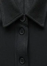 Blusa de punto negro con botonera frontal y mangas largas.