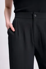 Pantalón negro de corte palazzo, con cintura alta y textura arrugada.
