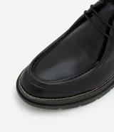 Zapato de vestir negro con cordones, fabricado en cuero sintético, con puntera redondeada y suela de goma.