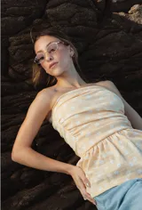 Top strapless color crema con estampado floral blanco, con frunces en el busto y detalle de volado en el ruedo.