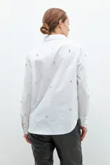 Camisa blanca con detalles de strass y perlas, de corte clásico y manga larga.