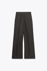 Pantalón blanco de tiro alto, corte ancho y largo cropped, confeccionado en mezcla de lino. Presenta bolsillos laterales, pinzas y raya planchada en delantero. Cierre frontal con cremallera, botón y ganchos metálicos.