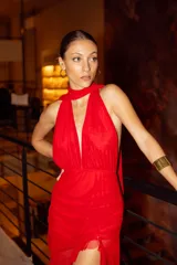 Vestido largo rojo de microtul, con escote halter profundo, pollera con frunces, abertura lateral y transparencias.
