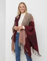 Ruana tejida con diseño colorblock en tonos borgoña, rosa viejo y beige. Presenta flecos en los bordes.