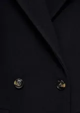 Abrigo cruzado de paño color negro, con cuello de solapa, doble botonadura frontal y bolsillos de solapa.