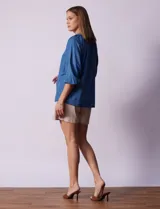 Blusa celeste de tencel con cuello a la base, escote en V con aplique de cordel y lazo de ajuste. Manga larga amplia con puño elastizado.