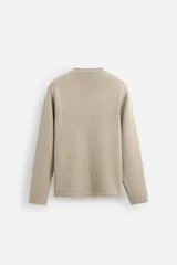 Jersey color beige de punto con cuello redondo y manga larga.