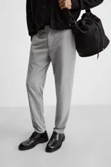 Pantalón negro de corte slim fit, confeccionado en tejido elástico. Cuenta con cintura elástica, bolsillos frontales y traseros de vivo. Cierre frontal con cremallera y botón.
