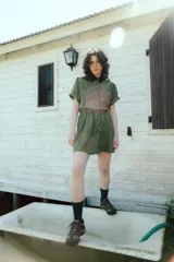 Vestido corto verde militar de microfibra con cuello camisero negro, cintura elastizada con cordón de ajuste y mangas cortas con dobladillo. Cierre frontal con botones.