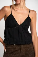 Blusa negra de algodón con breteles finos, escote en V con detalle de encaje y volado en el ruedo.
