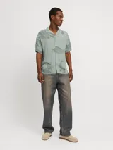 Camisa de viscosa LENZING™ ECOVERO™ color verde con estampado de peces y olas en gris, cuello resort, mangas cortas y corte relajado.