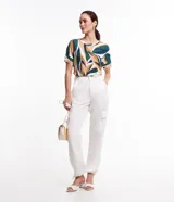 Blusa de viscosa con estampado de hojas en tonos verde, azul y ocre. Tiene cuello redondo y mangas cortas.
