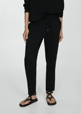 Pantalón negro de piqué con cintura elástica, tiro alto, diseño jogger, bolsillos laterales y costuras decorativas.
