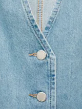 Chaleco de jean celeste con cuello en V, sin mangas, cierre frontal con botones y lazo ajustable en la cintura.