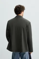 Blazer regular fit color gris oscuro confeccionada en tejido con estructura. Cuello con solapas de muesca y manga larga. Bolsillos de solapa en cadera. Cierre frontal de botonadura.