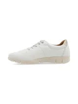 Sneaker de cuero blanco con talón dorado, cordones finos y suela beige con diseño anatómico.