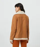 Campera marrón de terciopelo con cuello camisero y forro de sherpa color crema. Tiene cierre frontal con cremallera y bolsillos delanteros con cremallera.