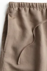 Short color beige de lino y viscosa, con cintura elástica ajustable con cordón y bolsillos laterales.