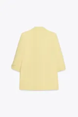 Blazer color marrón oscuro, de corte recto, con cuello solapa y hombreras. Tiene mangas 3/4 con trabilla y botón dorado, y bolsillos delanteros con solapa.