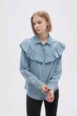 Camisa celeste de jean con cuello camisero, cierre con botones y volados en el cuello y el frente.