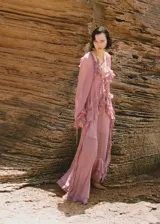 Vestido largo color rosa viejo, de tela traslúcida con volados y mangas largas abullonadas.