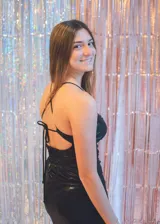 Vestido corto color fucsia con textura brillante, breteles finos y escote recto. Presenta corte tipo corsé con costuras fruncidas y falda ajustada.