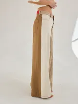 Pantalón ancho de denim con diseño patchwork en diferentes tonos de azul, con tiro alto, corte holgado y cierre frontal con botones.